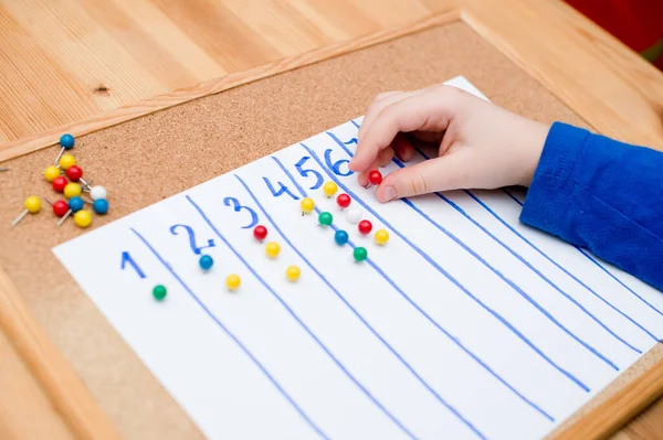 Little child doing simple math exercises. Early education, counting game. Preschool exercise for kids. Child learn to count to ten. Montessori math tool.