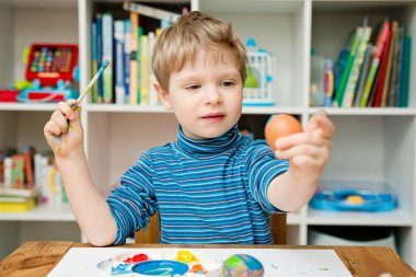 Mutlu Paskalyalar. Paskalya yumurtası boyayan 3 yaşında bir çocuk. Dini bayram. Erken eğitim ve sanatsal anaokulu aktiviteleri.