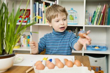 Mutlu Paskalyalar. Paskalya yumurtası boyayan 3 yaşında bir çocuk. Dini bayram. Erken eğitim ve sanatsal anaokulu aktiviteleri.