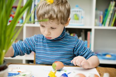 Mutlu Paskalyalar. Paskalya yumurtası boyayan 3 yaşında bir çocuk. Dini bayram. Erken eğitim ve sanatsal anaokulu aktiviteleri.