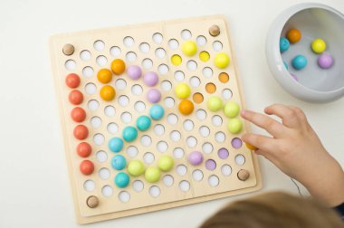 123, çocuk sayı yaratmak için pimi yerleştiriyor. İyi motor becerileri, matematiksel temel.