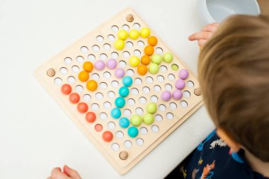 123, çocuk sayı yaratmak için pimi yerleştiriyor. İyi motor becerileri, matematiksel temel.