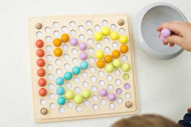 123, çocuk sayı yaratmak için pimi yerleştiriyor. İyi motor becerileri, matematiksel temel.