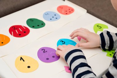 Beyaz masada farklı renkte kağıt yumurtalar. Paskalya temalı oyun, figürün diğer tarafını bul.