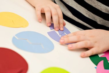Beyaz masada farklı renkte kağıt yumurtalar. Paskalya temalı oyun, figürün diğer tarafını bul.