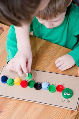 Plastik şişe kapağı solucanı. Doğru renk ponponları kırkayak tırtılına koyun. 5 dakikalık aralıklarla. Çocuk yuvası aktivitesi. Erken eğitim, iyi motor becerileri..