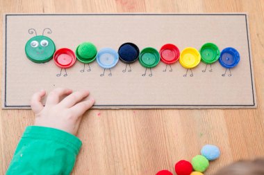 Plastik şişe kapağı solucanı. Doğru renk ponponları kırkayak tırtılına koyun. 5 dakikalık aralıklarla. Çocuk yuvası aktivitesi. Erken eğitim, iyi motor becerileri..