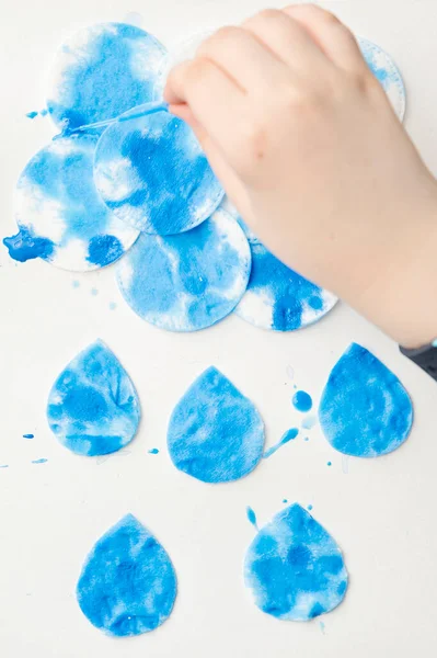 Let's make the rain. Boy coloring drop shape cotton pads. 5 minute crafts for children activities. Creative solutions at home.