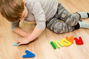 İki yaşındaki bir çocuk keçeli harflerden ismini çeviriyor. Okumayı öğrenmek.