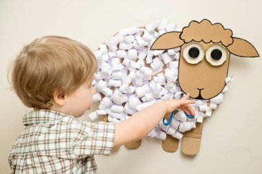 Çocuk bir kağıt koyun kesti. Oyuncak bebek. Evde faaliyet var. Erken eğitim, iyi motor beceriler. Montessori yöntembilimi.