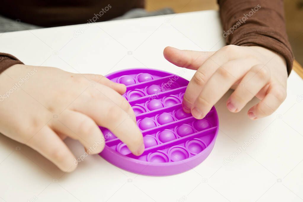 Close up shot of kids fingers on pop it fidget toy. Instrument for sequence, fine motor skills, therapy task for education and brain exercise. Learn to start counting, do primary arithmetic operation