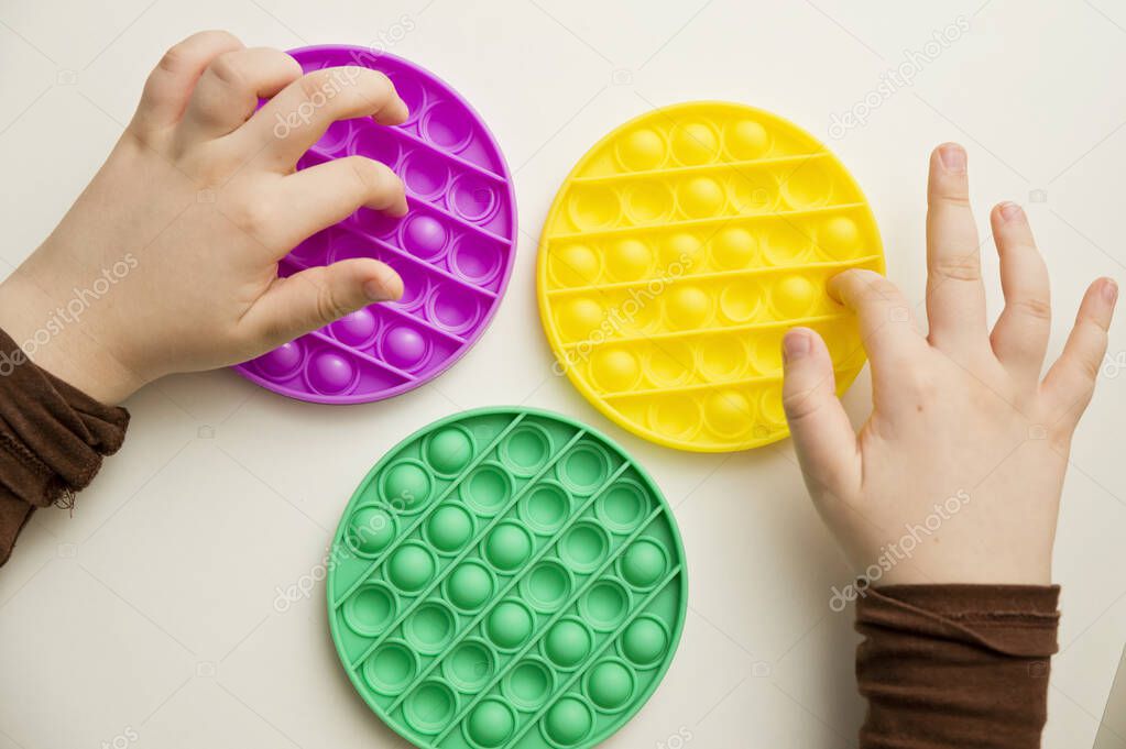 Close up shot of kids fingers on pop it fidget toy. Instrument for sequence, fine motor skills, therapy task for education and brain exercise. Learn to start counting, do primary arithmetic operation