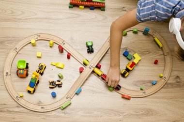 Çocuk tahta oyuncaklarla oynuyor. Tren rayları, ahşap blok binalar.