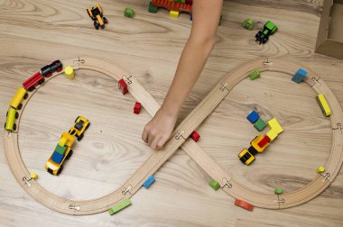Çocuk tahta oyuncaklarla oynuyor. Tren rayları, ahşap blok binalar.
