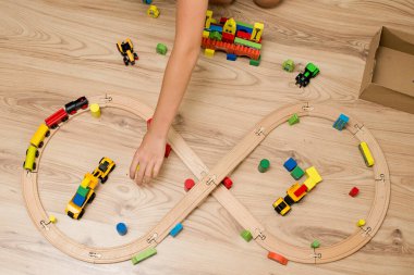 Çocuk tahta oyuncaklarla oynuyor. Tren rayları, ahşap blok binalar.