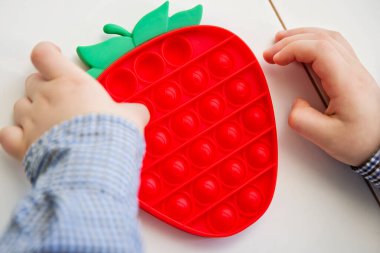 Çocuk çilek şekilli duyusal oyuncakla oynuyor. İnce motor becerileri için araç, saymaya başlamak için araç, birincil aritmetik işlemlerini öğren.