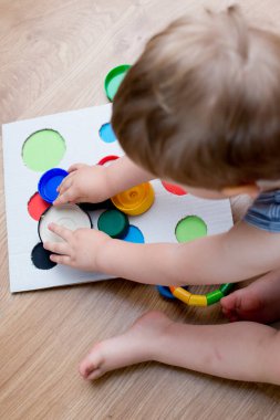 Bir eşleşme bul. Çocuk farklı boyut ve renkte plastik başlıkları eşleşen deliklere sokuyor. Dolayısıyla eğitim ve beyin egzersizi için terapi görevi. DIY oyun oynuyor. çocuklar ve engelliler için iyi motor becerileri