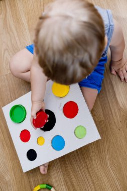 Bir eşleşme bul. Çocuk farklı boyut ve renkte plastik başlıkları eşleşen deliklere sokuyor. Dolayısıyla eğitim ve beyin egzersizi için terapi görevi. DIY oyun oynuyor. çocuklar ve engelliler için iyi motor becerileri