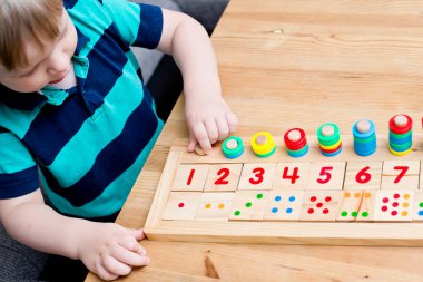 Çocuk farklı renkte ahşap halkalarla oynuyor. Sıralama, iyi motor beceriler, eğitim ve beyin egzersizi için terapi görevi. Matematik oyunu da dahil. Montessori tipi uygulama. Tahta oyuncaklar.