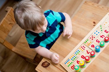 Çocuk farklı renkte ahşap halkalarla oynuyor. Sıralama, iyi motor beceriler, eğitim ve beyin egzersizi için terapi görevi. Matematik oyunu da dahil. Montessori tipi uygulama. Tahta oyuncaklar.