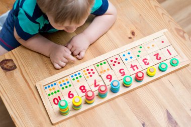 Çocuk farklı renkte ahşap halkalarla oynuyor. Sıralama, iyi motor beceriler, eğitim ve beyin egzersizi için terapi görevi. Matematik oyunu da dahil. Montessori tipi uygulama. Tahta oyuncaklar.