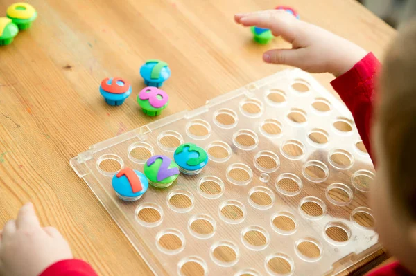 Counting game. Collect correct amount of caps by assigned number. Little boy perform the task. early education. Toy learn stimulate imagination, creativity, hand-eye coordination.