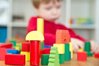 Genç bir inşaatçı. Çocuk ahşap bloklardan şehir inşa ediyor. Çocuk Oyun Odası. Geliştirme ve İnşaat Konsepti.