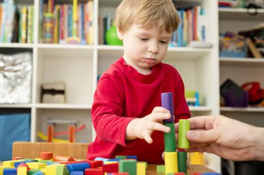 Genç bir inşaatçı. Çocuk ahşap bloklardan şehir inşa ediyor. Çocuk Oyun Odası. Geliştirme ve İnşaat Konsepti.