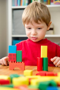 Genç bir inşaatçı. Çocuk ahşap bloklardan şehir inşa ediyor. Çocuk Oyun Odası. Geliştirme ve İnşaat Konsepti.