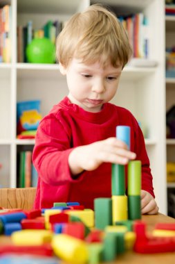 Genç bir inşaatçı. Çocuk ahşap bloklardan şehir inşa ediyor. Çocuk Oyun Odası. Geliştirme ve İnşaat Konsepti.