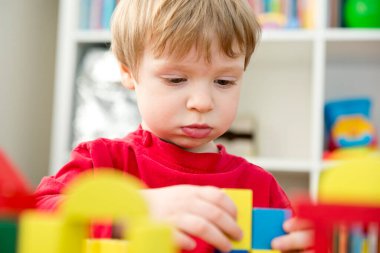 Genç bir inşaatçı. Çocuk ahşap bloklardan şehir inşa ediyor. Çocuk Oyun Odası. Geliştirme ve İnşaat Konsepti.