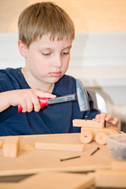 Kid Playing with DIY Toys Carpentry Construction Engineering Tool Workshop Kit. Artistic face expression. 