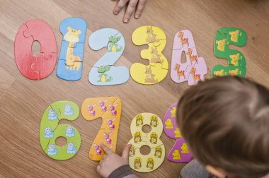 Yeni yürümeye başlayan çocuk yerde oyuncak numaralarıyla oynuyor. Entelektüel matematik oyunu, erken eğitim için anaokulu uygulaması.