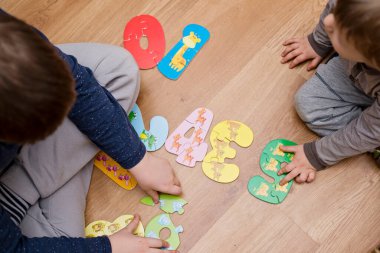 Yeni yürümeye başlayan çocuk yerde oyuncak numaralarıyla oynuyor. Entelektüel matematik oyunu, erken eğitim için anaokulu uygulaması.