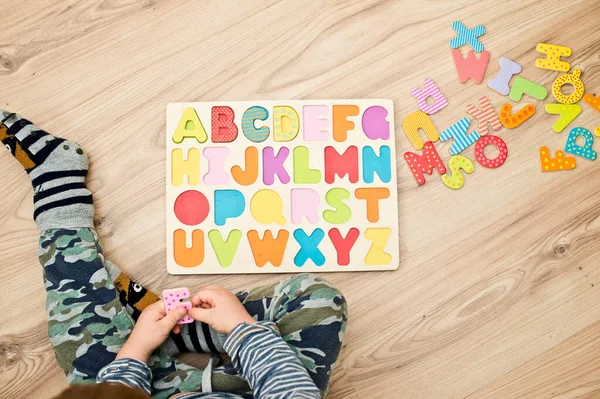 Baby early learning. Wooden letters of the alphabet. Children reading puzzle. Kids educational game, match the right place. Teaching develop intellectual kid game board.