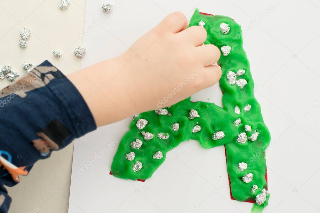 Two year boy decorating play dough letter 