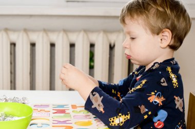 Tahta alfabe harfleriyle oynayan iki yaşında bir çocuk. Folyoya sarılı mektuplar. Entellektüel oyun, erken eğitim için anaokulu uygulaması. Sözlü ve bellek alıştırması.