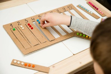 Pamuk yumaklarıyla kayışları numaralandırılmış oyuğa yerleştirin. Anaokulları için okul öncesi eğitim yardımı. Çocuklar erken yaşta zeka için montessori setini öğreniyorlar.