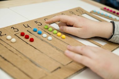 Pamuk yumaklarıyla kayışları numaralandırılmış oyuğa yerleştirin. Anaokulları için okul öncesi eğitim yardımı. Çocuklar erken yaşta zeka için montessori setini öğreniyorlar.