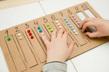 Pamuk yumaklarıyla kayışları numaralandırılmış oyuğa yerleştirin. Anaokulları için okul öncesi eğitim yardımı. Çocuklar erken yaşta zeka için montessori setini öğreniyorlar.