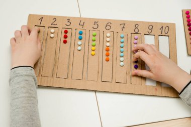 Pamuk yumaklarıyla kayışları numaralandırılmış oyuğa yerleştirin. Anaokulları için okul öncesi eğitim yardımı. Çocuklar erken yaşta zeka için montessori setini öğreniyorlar.