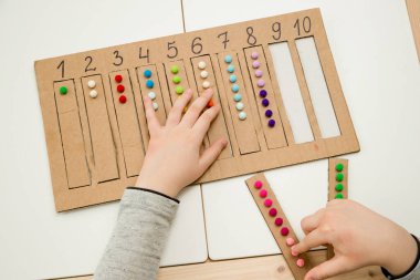 Pamuk yumaklarıyla kayışları numaralandırılmış oyuğa yerleştirin. Anaokulları için okul öncesi eğitim yardımı. Çocuklar erken yaşta zeka için montessori setini öğreniyorlar.