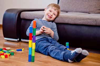 Genç bir inşaatçı. Çocuk ahşap bloklardan şehir inşa ediyor. Çocuk Oyun Odası. Geliştirme ve İnşaat Konsepti. Öğrenme oyuncağı hayal gücünü, yaratıcılığı, el-göz koordinasyonunu canlandırır..