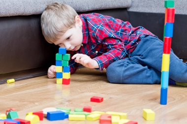 Genç bir inşaatçı. Çocuk ahşap bloklardan şehir inşa ediyor. Çocuk Oyun Odası. Geliştirme ve İnşaat Konsepti. Öğrenme oyuncağı hayal gücünü, yaratıcılığı, el-göz koordinasyonunu canlandırır..