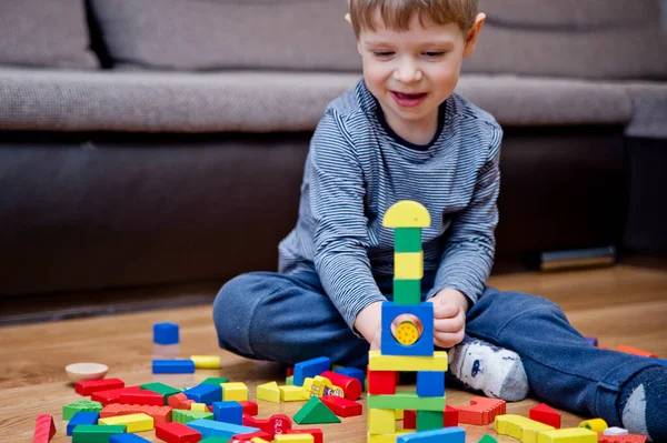 Genç bir inşaatçı. Çocuk ahşap bloklardan şehir inşa ediyor. Çocuk Oyun Odası. Geliştirme ve İnşaat Konsepti. Öğrenme oyuncağı hayal gücünü, yaratıcılığı, el-göz koordinasyonunu canlandırır..