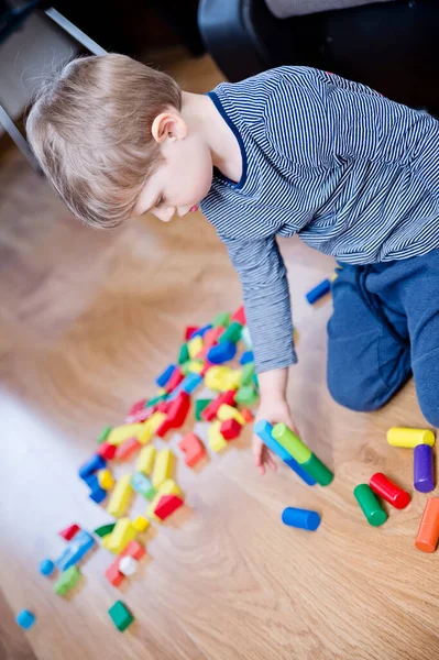 Genç bir inşaatçı. Çocuk ahşap bloklardan şehir inşa ediyor. Çocuk Oyun Odası. Geliştirme ve İnşaat Konsepti. Öğrenme oyuncağı hayal gücünü, yaratıcılığı, el-göz koordinasyonunu canlandırır..