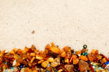 Yıldızlar kayıyor. Kehribar ve boncuklar beyaz kum arka planda.