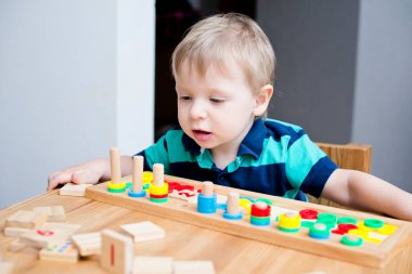 Çocuk farklı renkte ahşap halkalarla oynuyor. Sıralama, iyi motor beceriler, eğitim ve beyin egzersizi için terapi görevi. Matematik oyunu da dahil. Montessori tipi uygulama. Tahta oyuncaklar.