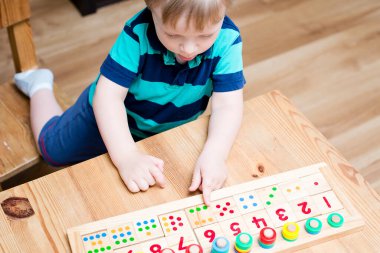 Çocuk farklı renkte ahşap halkalarla oynuyor. Sıralama, iyi motor beceriler, eğitim ve beyin egzersizi için terapi görevi. Matematik oyunu da dahil. Montessori tipi uygulama. Tahta oyuncaklar.