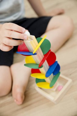 Tahta mermer yarış kulesi. Çocuklar oyun oynamak için oyun oynarlar. Çocuk topu başlangıç pozisyonuna getiriyor. Evdeki etkinlikler. Tablo ve zemin oyunu.